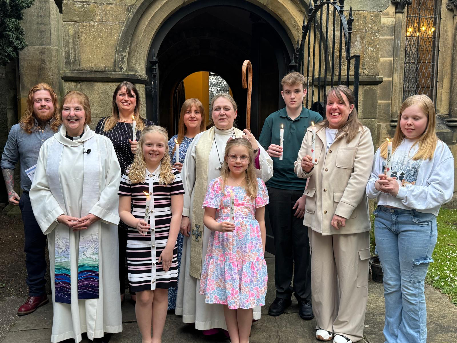 Bishop Leah Vasey-Saunders with the seven newly confirmed candidates from Finningley and St Michael's, holding lit candles at the church door