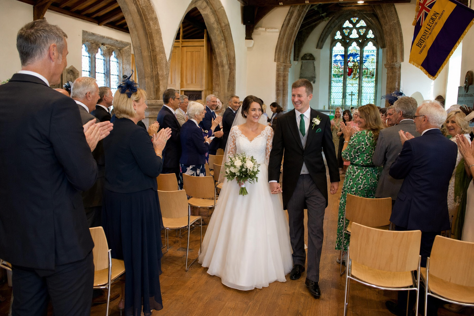A newly married couple walking back down the aisle as guests applaud